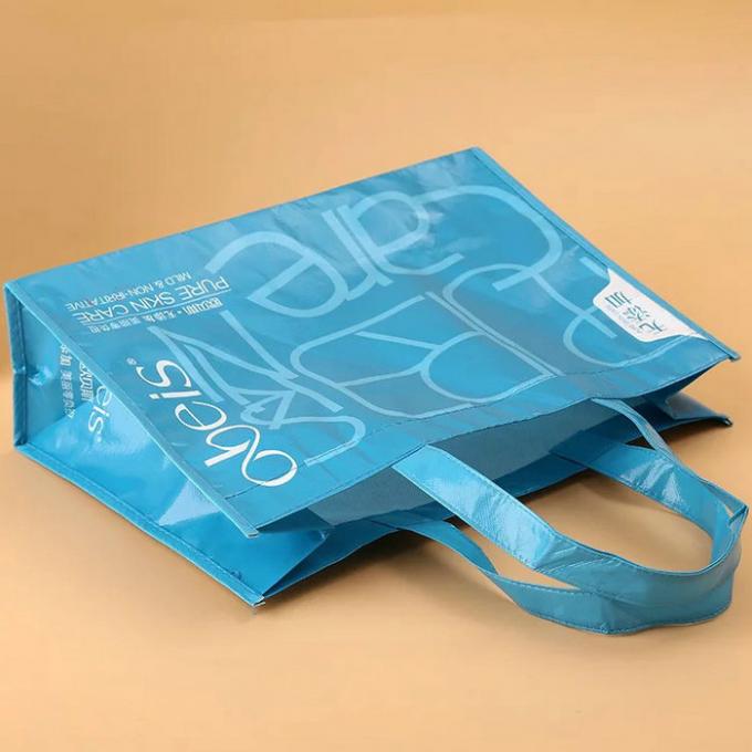 Πτυσσόμενες μπλε μη υφαμένες τσάντες δώρων, τοποθετημένες σε στρώματα μη υφαμένες επαναχρησιμοποιήσιμες τσάντες
