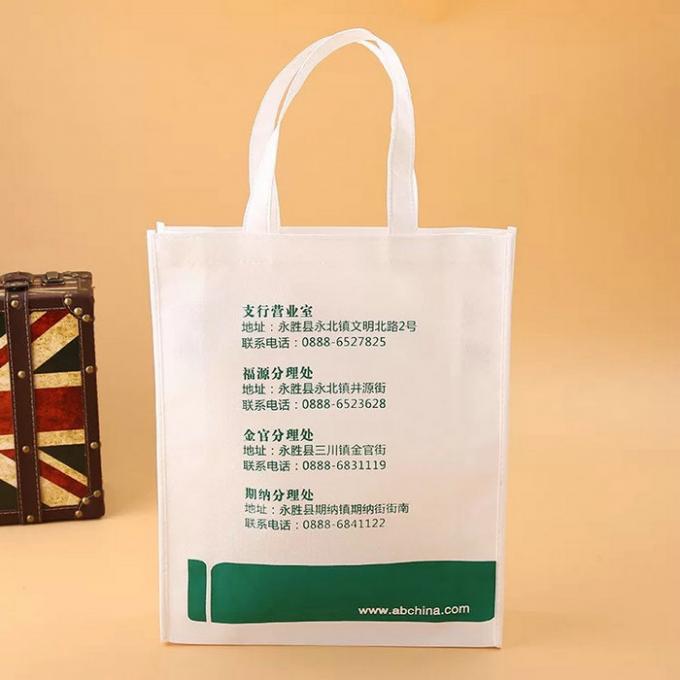 Άσπρες και πράσινες μη υφαμένες τσάντες υφάσματος με το τυπωμένο λογότυπο στην επιφάνεια